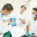 Dentistry education. Female dentist doctor teacher explaining treatment procedure to male iranian asian students in dental clinic